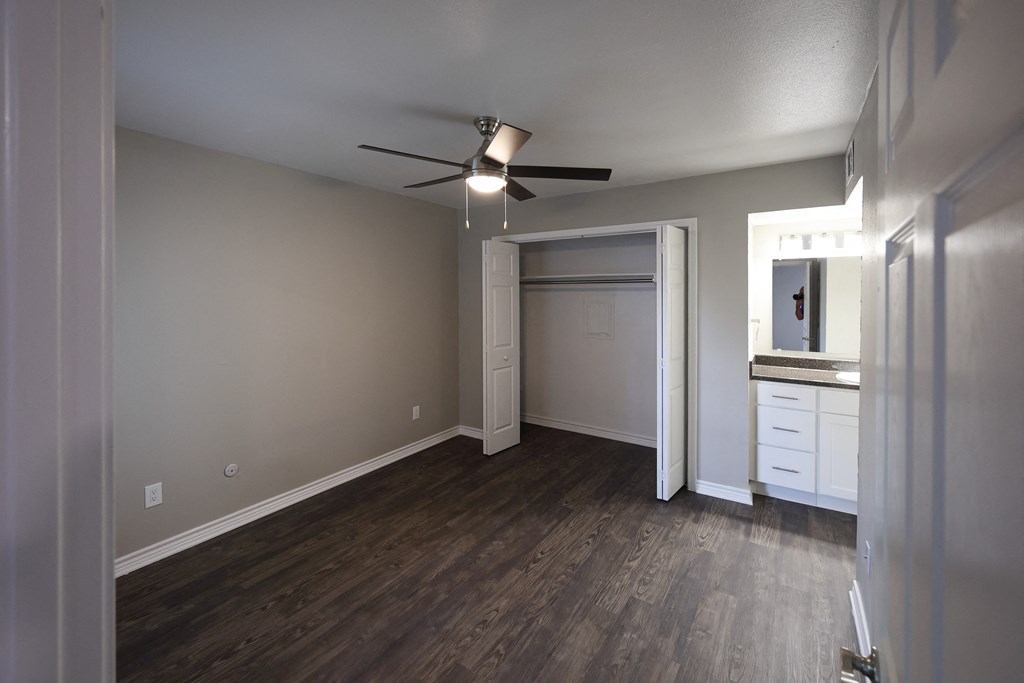 View of bedroom with bi-fold door closet, ceiling fan, and view of bathroom vanity