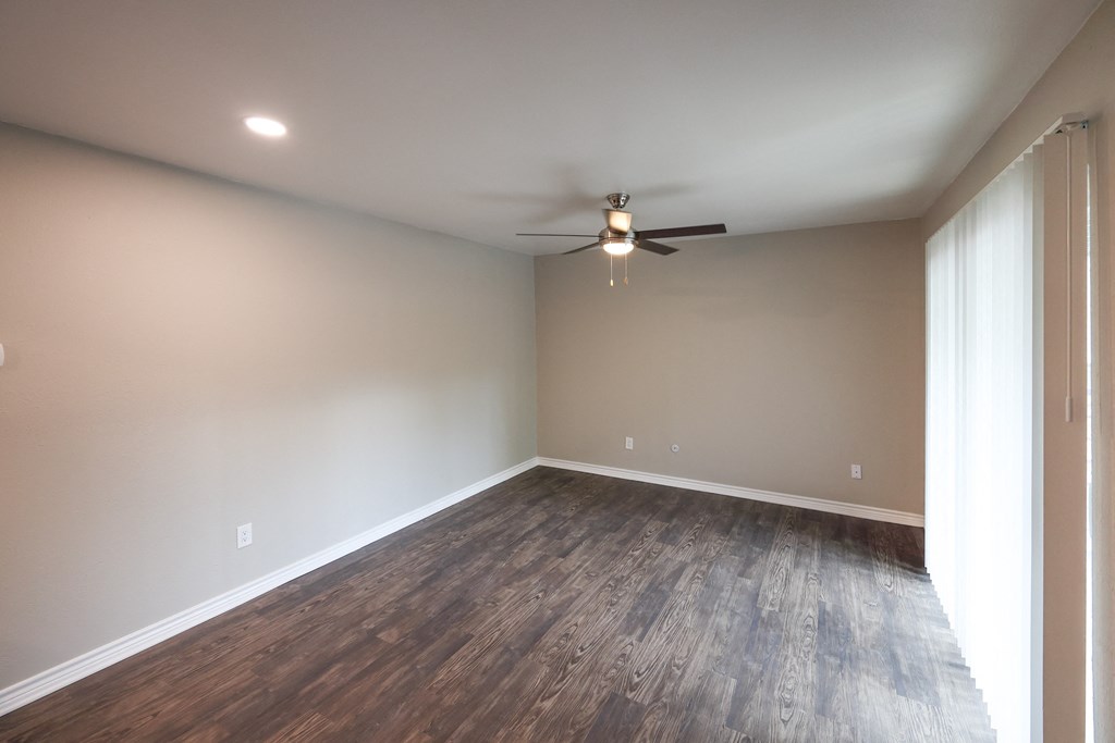 Living area view with wood look flooring, ceiling fan, and sliding glass door access to patio