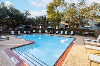 a swimming pool with chairs and trees in the background