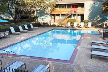 a swimming pool with chairs and a building in the background