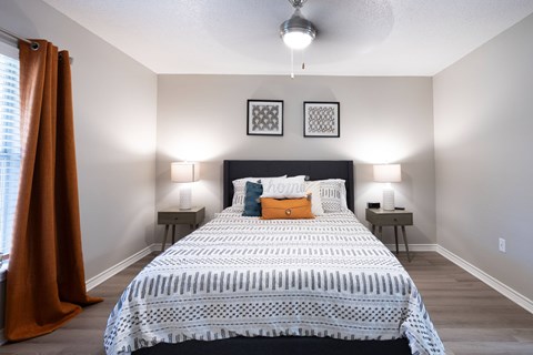 A bedroom with a large bed and two lamps.