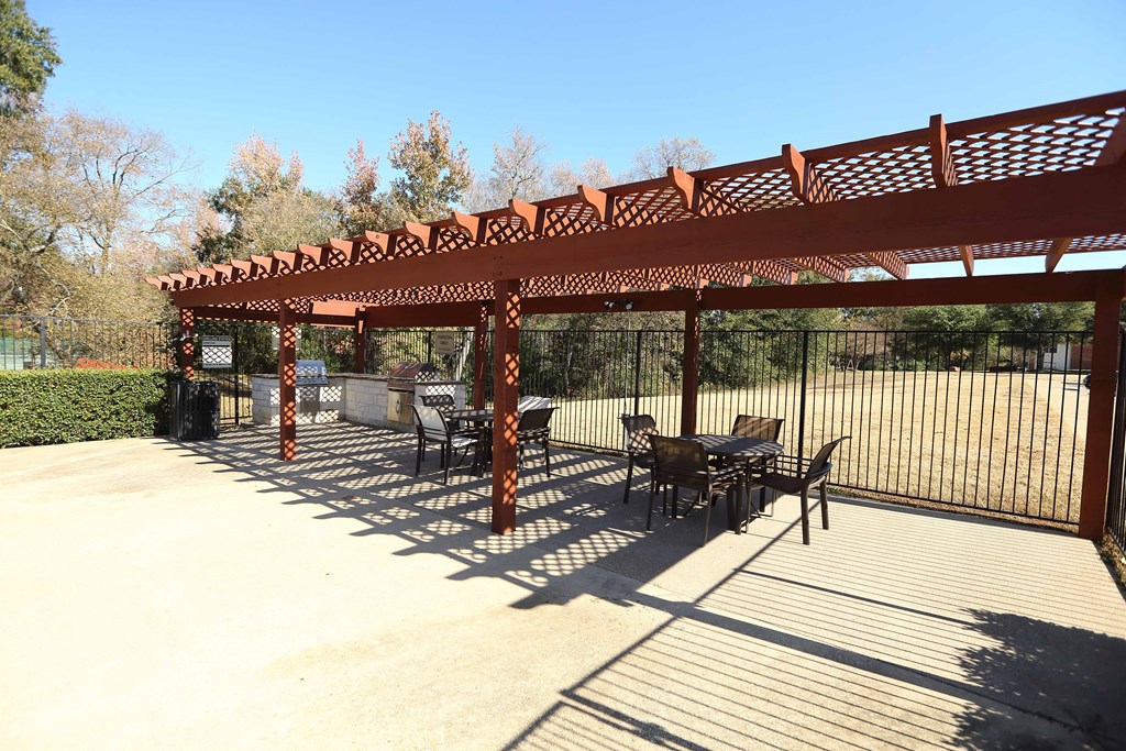View of grilling station in fenced pool area with counters to prep food and seating