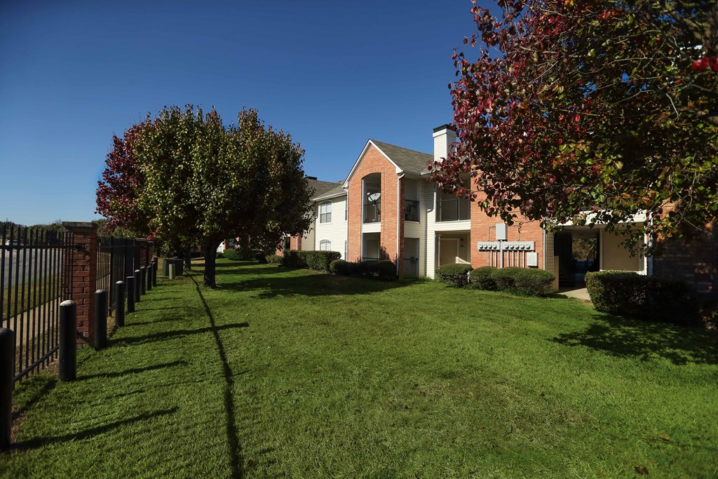 View of gated property, exterior building, and lush grass and trees