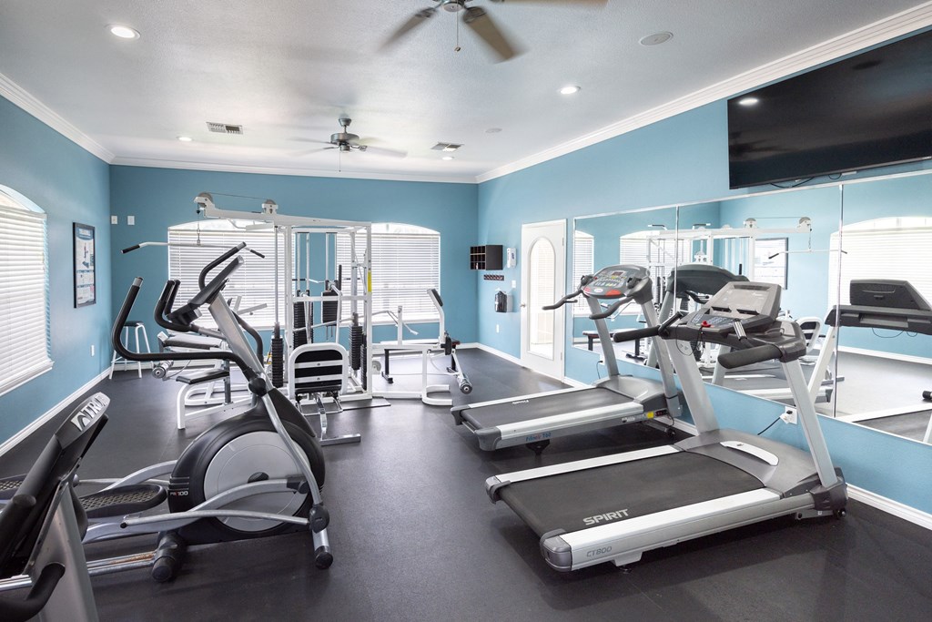 View of community fitness center with stationary bike, elliptical, treadmills and weight machine