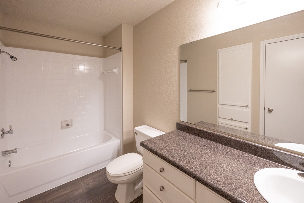 Alternate view of bathroom with large vanity counter, mirror, toilet, and tiled tub shower combo