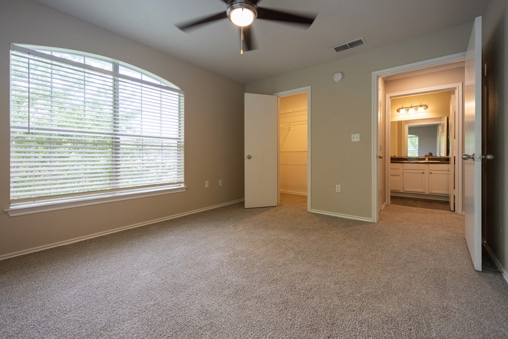 Alternate view of guest bedroom looking into walk in closet and bathroom across the hall. On second floor with carpet, ceiling fan, and well lit window