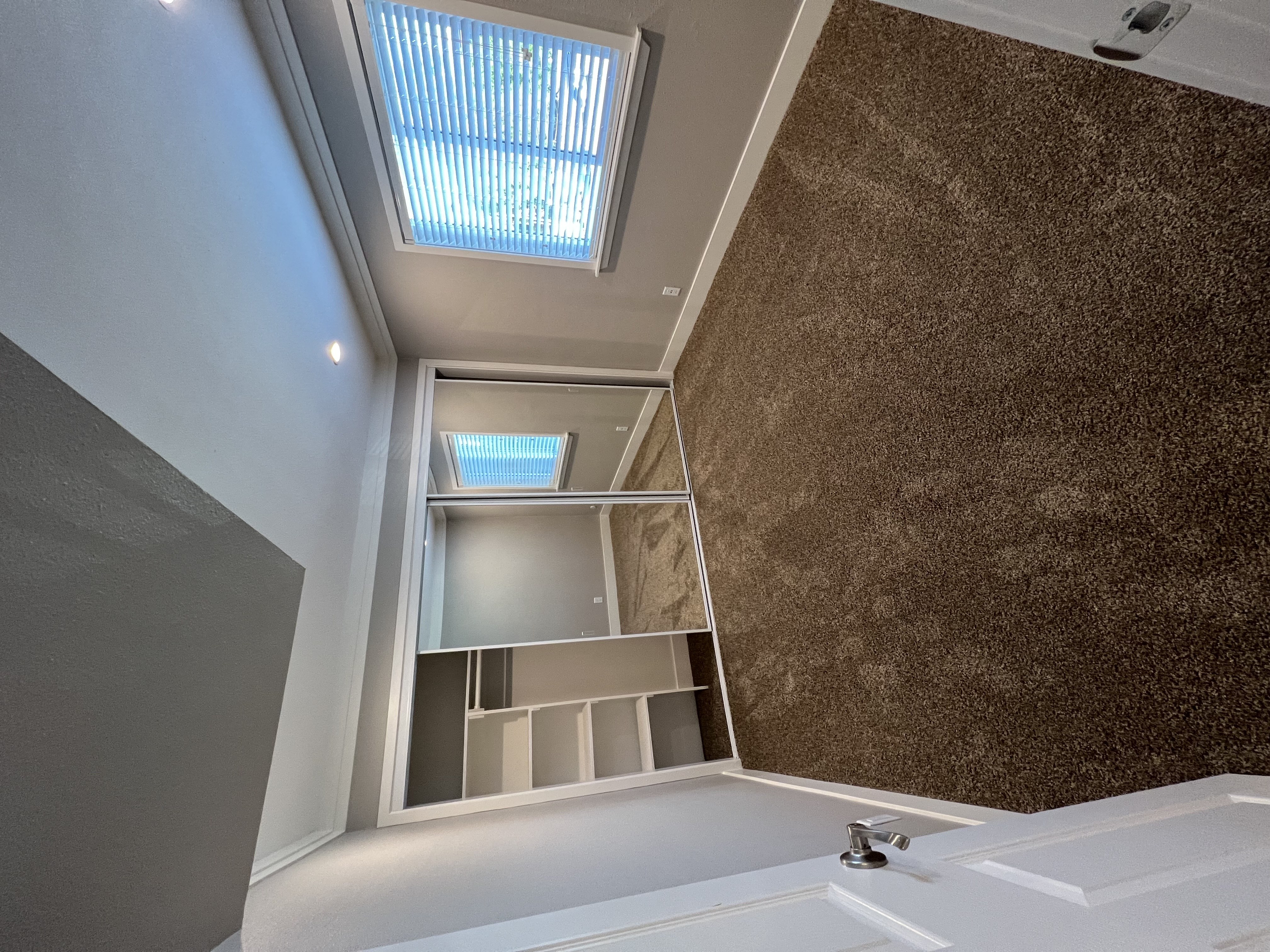 View of bedroom with carpet flooring, sliding mirror closet door with built in shelving, and well lit window