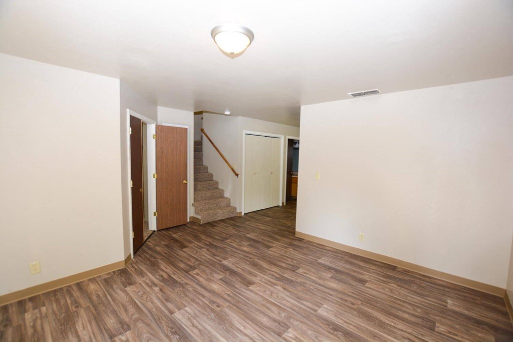 Living room view with wood look flooring, stairs leading to upstairs bedrooms, and hall way