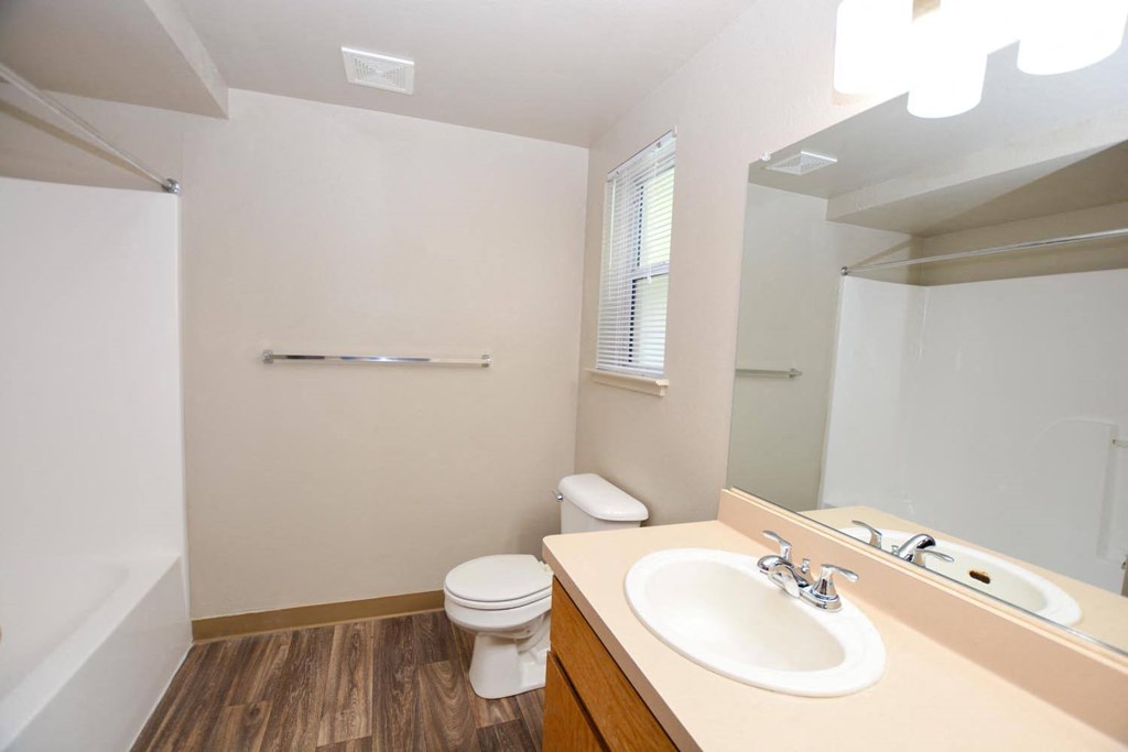 View of bathroom with vanity, sink, large mirror, toilet, tub shower combo and window