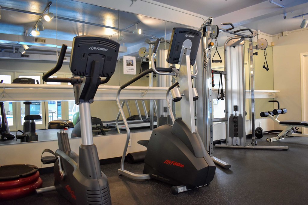 View of community gym featuring stationary bike, stair stepper, and weight machine
