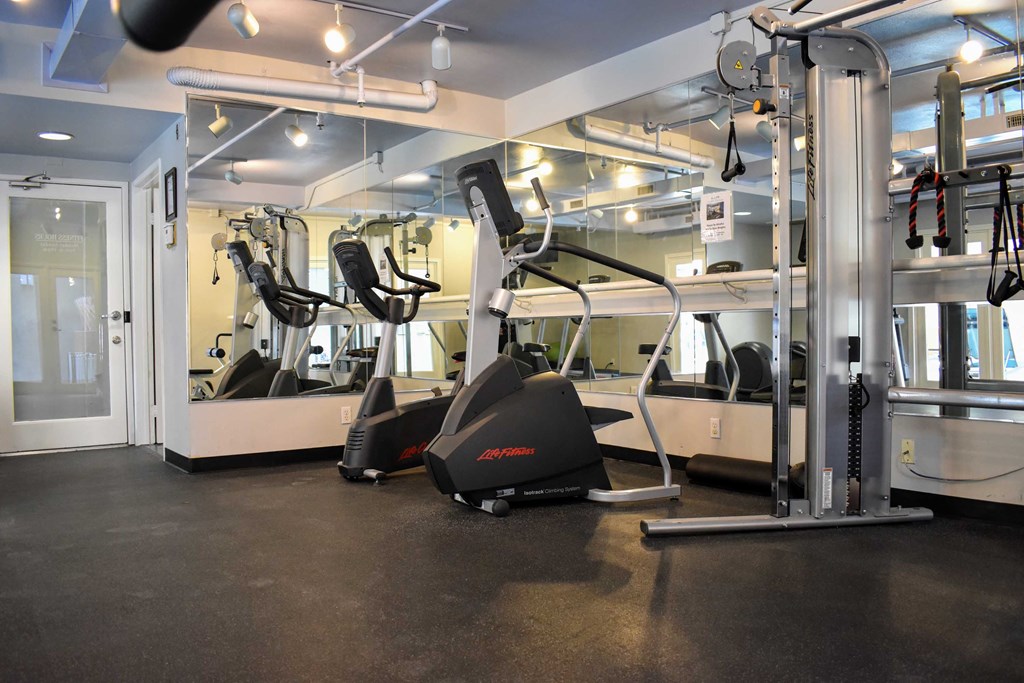View of community gym featuring stationary bike, stair stepper, and weight machine