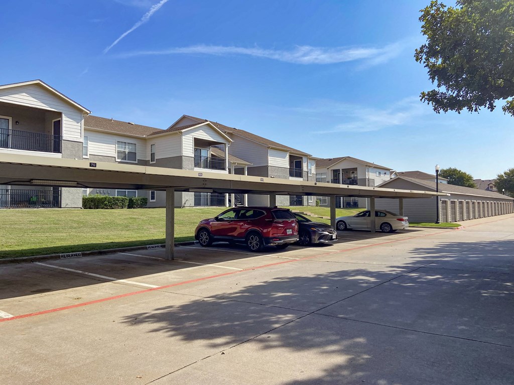 View of covered parking area and exteriors of buildings in back ground