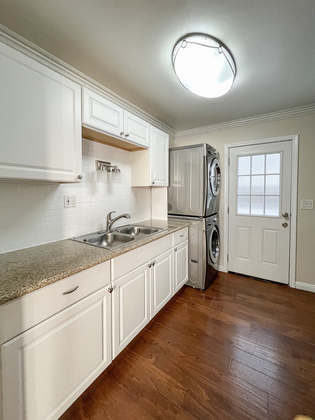 kitchen with granite counters, wood floors, and stacked washer dryer
