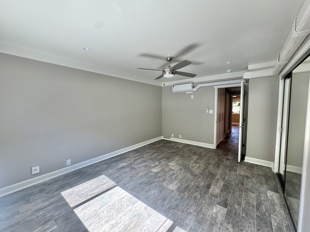 A room with a ceiling fan and light fixture, and a doorway leading to another room.