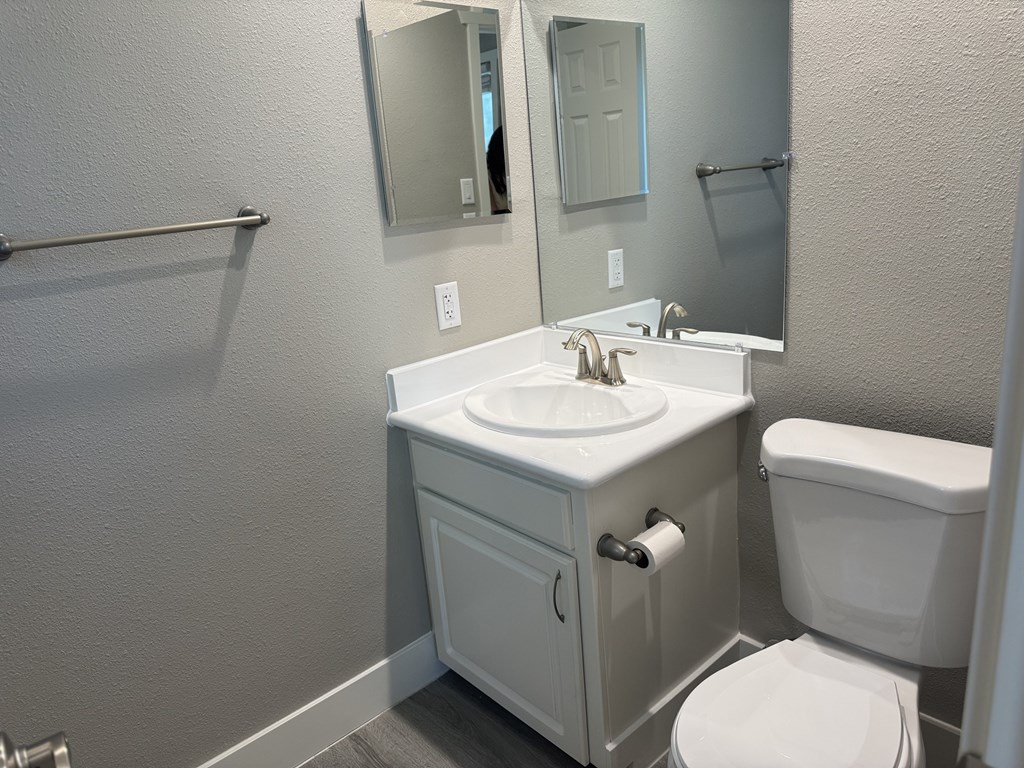 A white bathroom with a sink, toilet and mirror.