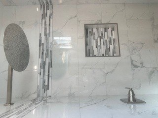 A bathroom with a marble wall and a shower.