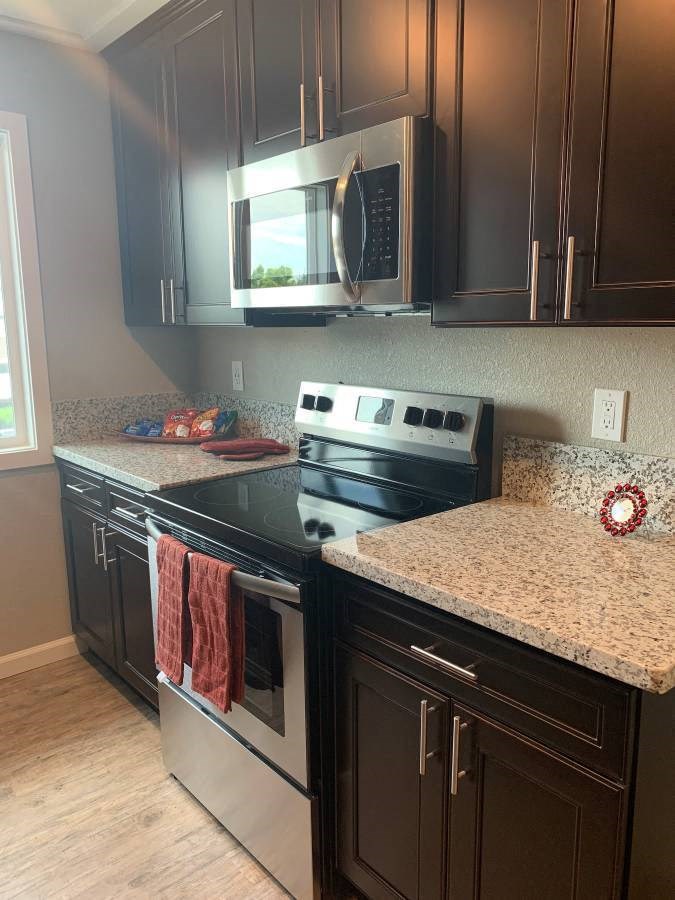 View of kitchen with brown cabinets, stainless appliances, and wood look flooring