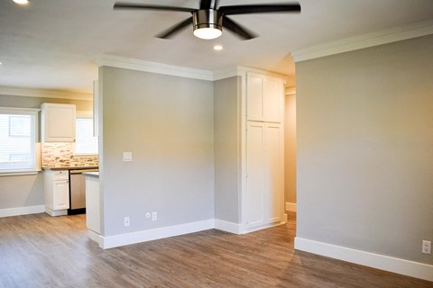 an empty living room and kitchen with a ceiling fan