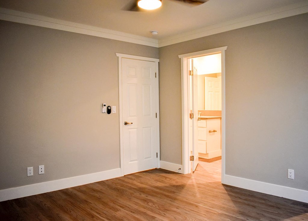 View of bedroom with wood-like flooring leading into bathroom.