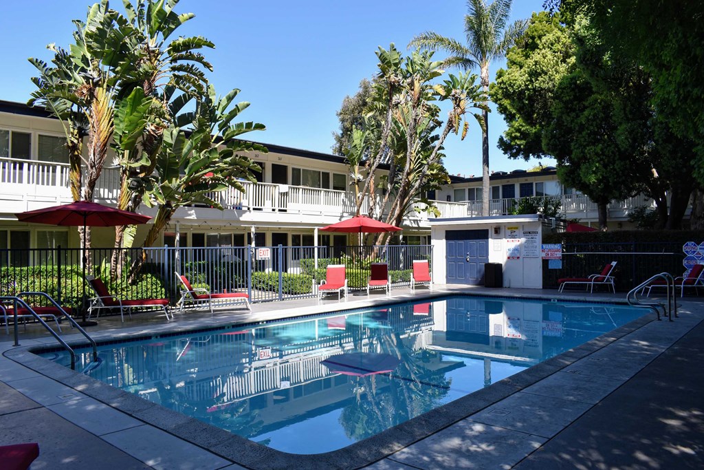 View of gated community pool with lounge chair and seating