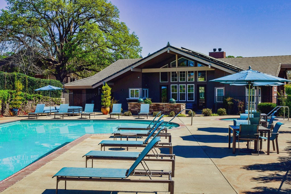 View of pool and club room, lounge chairs, and seating