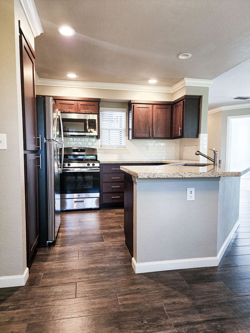 Kitchen Kitchen view with brown cabinets, stone counters, tile backsplash, and stainless appliances