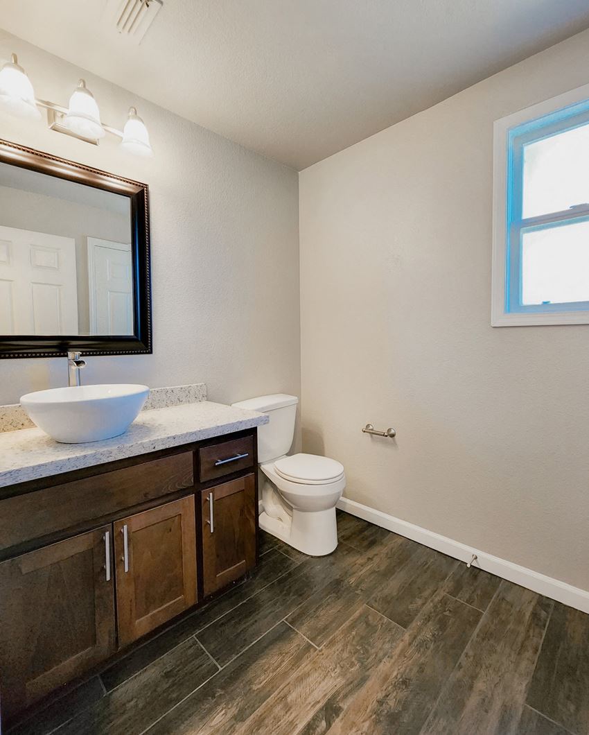 Bathroom View of bathroom vanity with vessel sink, large mirror, toilet, and well lit window.