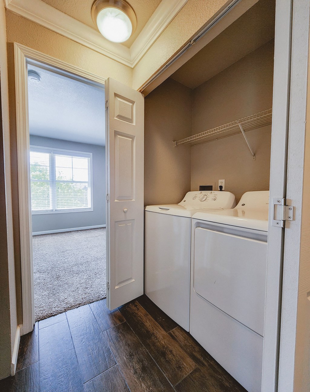 Utility room with washer and dryer and shelving above