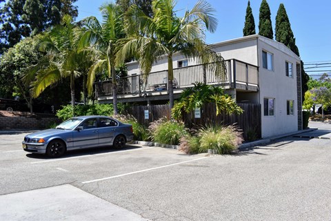 A blue car is parked in front of a two-story building.