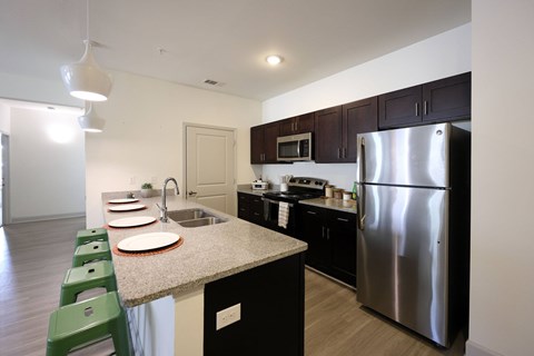 A kitchen with a stainless steel refrigerator and green chairs.