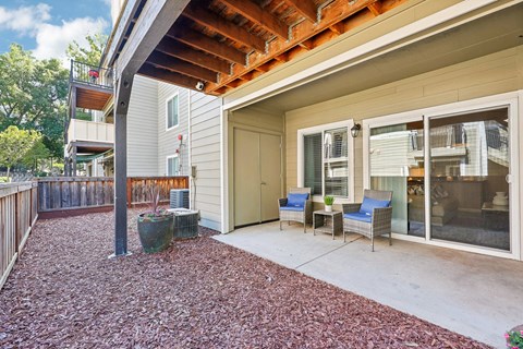 a covered patio with chairs and a sliding glass door