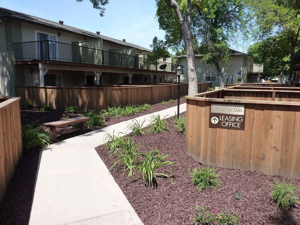 View of sidewalk winding through property showcasing private patio/balcony and nice landscaping