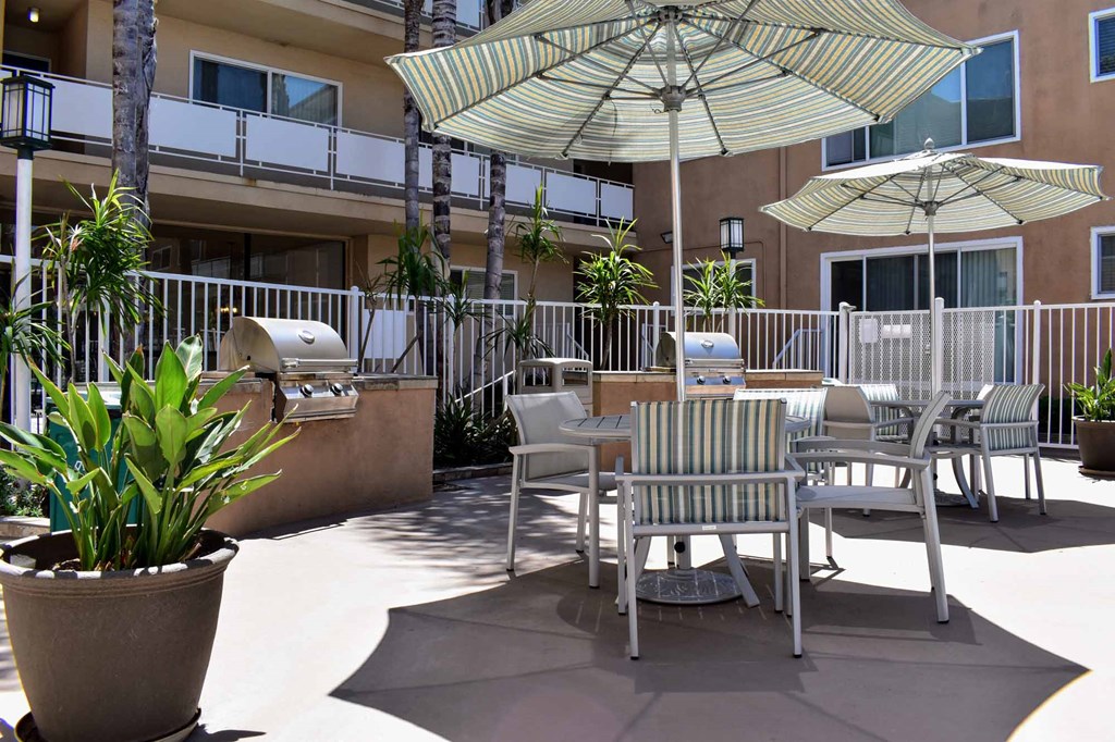 View of community grilling area with counters to prep food, seating under umbrellas