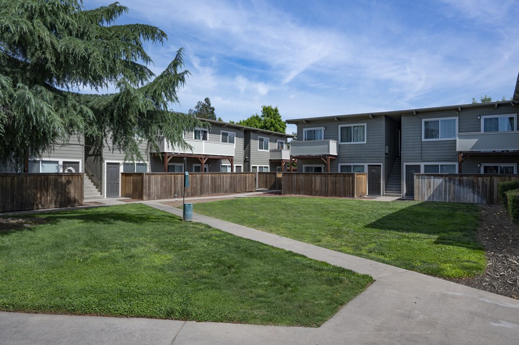 a row of apartment buildings with a lawn and sidewalk