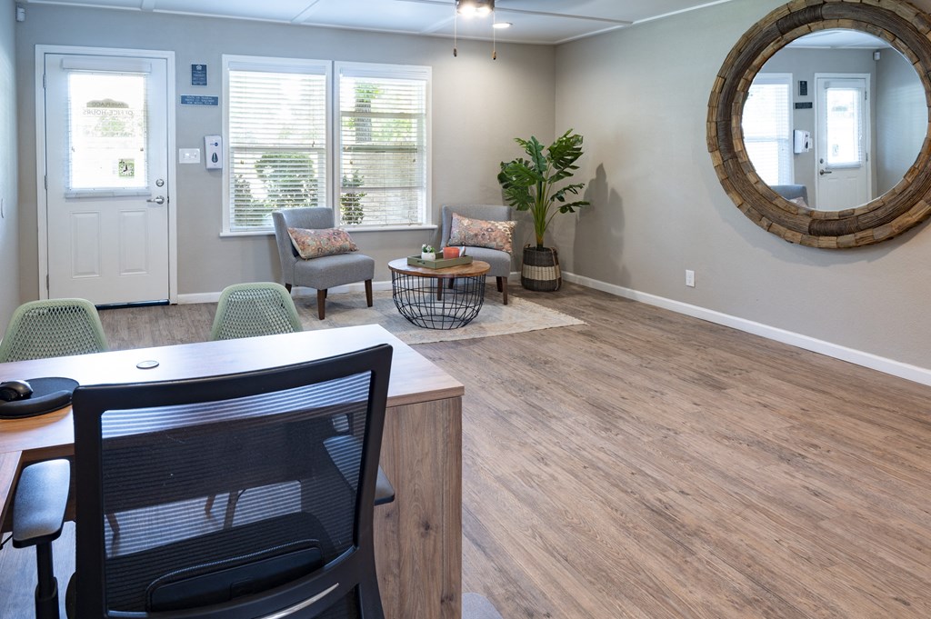 a living room with a table and chairs and a mirror on the wall