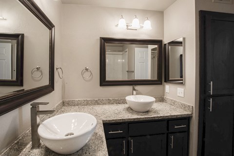 View of bathroom vanity with two vessel sinks and two mirrors with lighting