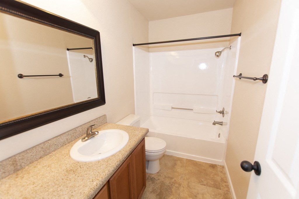 View of bathroom with vanity space, large mirror, toilet, and tub shower combo