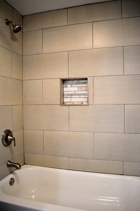 bathtub and shower combo with tiled walls