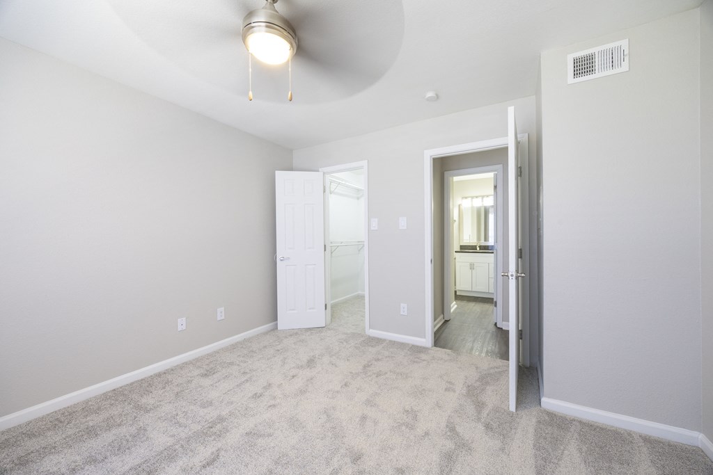 an empty living room with white carpet and a white door to a bathroom