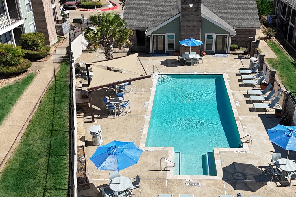 A pool with a blue umbrella and a white umbrella.