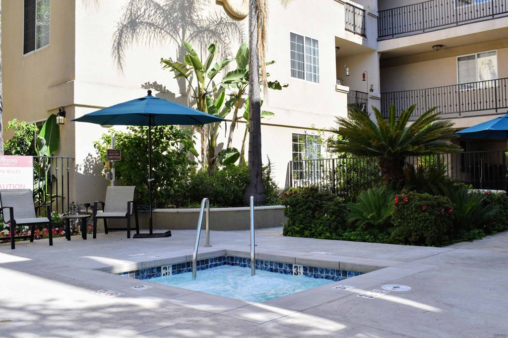 spa View of spa with seating and umbrella and tropical landscaping