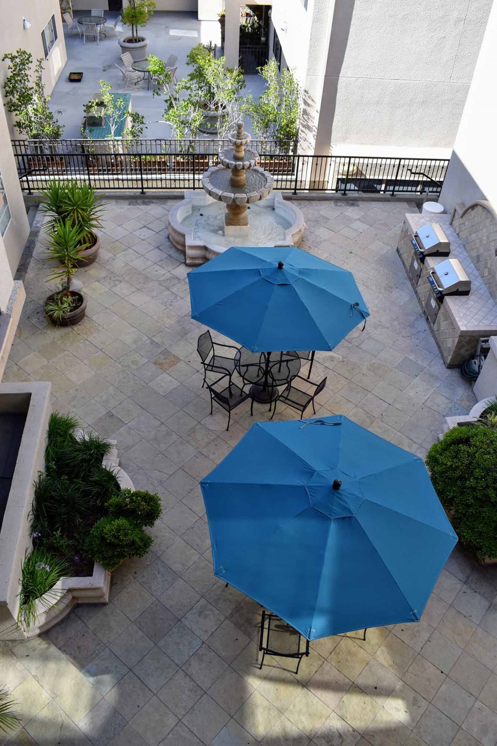 Wlwvated view into courtyard with seating areas with umbrella coverings, grilling station with multiple grills and counterspace to prep food, and fountain