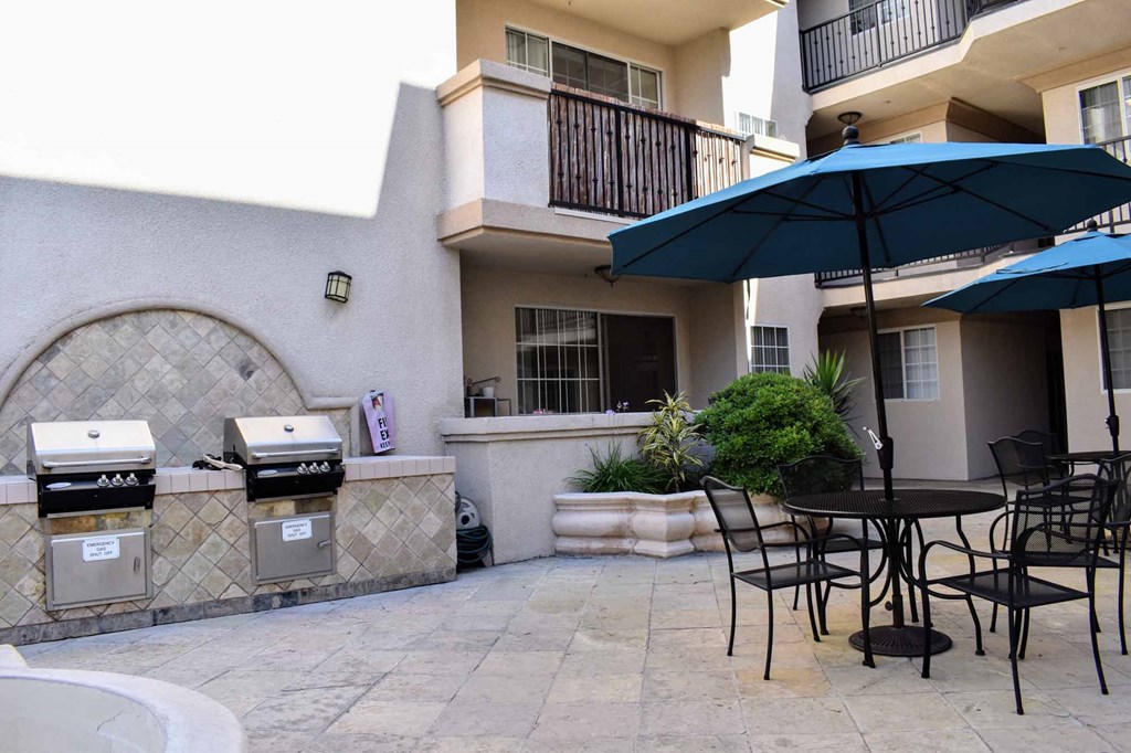 Courtyard view with seating with umrellas, grilling station with two grills and counter space to prep food.