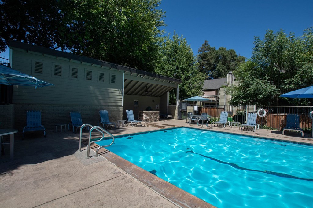 View of swimming pool with seating under umbrellas and lounge chairs