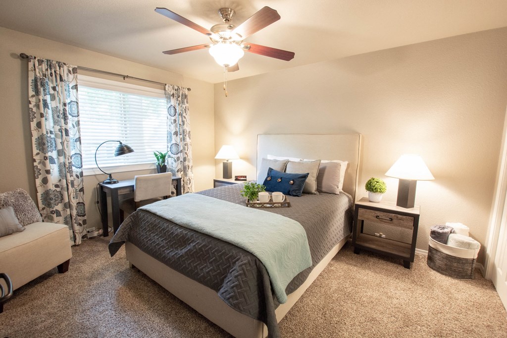 view of a furnished bedroom with ceiling fan carpet flooring, and well lit window