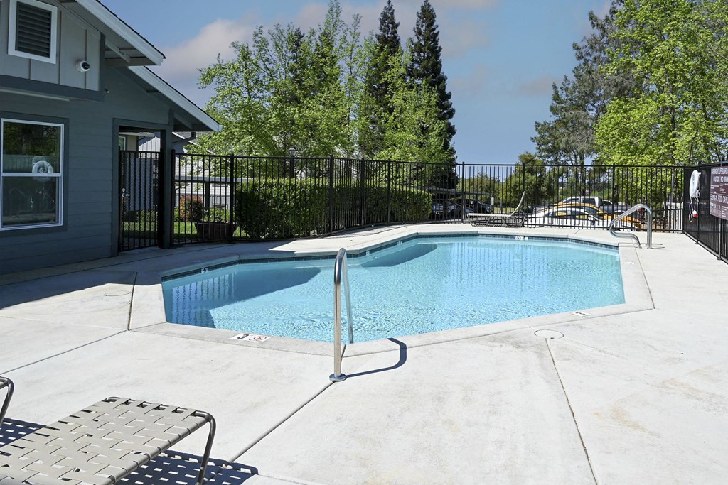 a pool with a fence around it and a house in the background at Sierra Oaks Living Apartments, Cameron Park, California