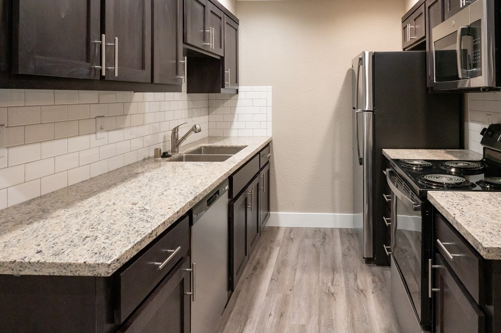 renovated kitchen with granite countertops and stainless steel appliances at the preserve at greatstone at Sierra Oaks Living Apartments, Cameron Park, CA