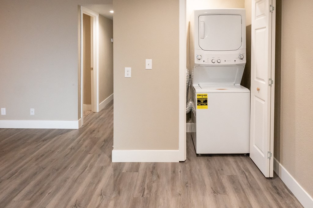a laundry room with a washer and dryer and a door to a hallway at Sierra Oaks Living Apartments, California