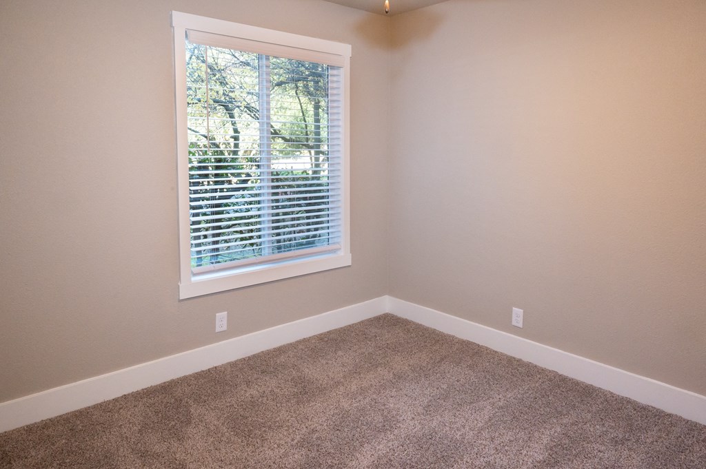 an empty room with carpet and a window at Sierra Oaks Living Apartments, Cameron Park, California