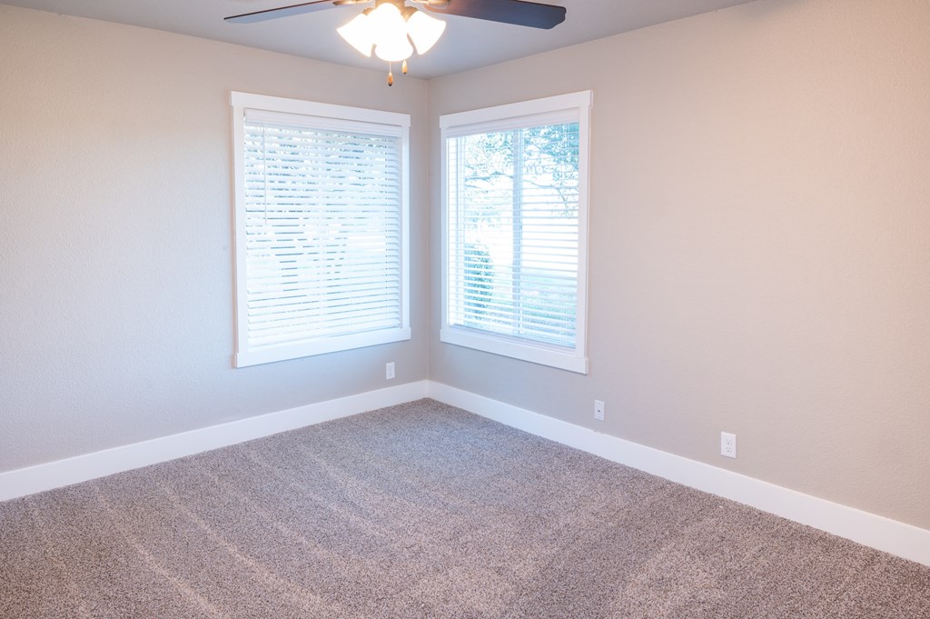 an empty room with two windows and a ceiling fan at Sierra Oaks Living Apartments, Cameron Park, CA 95682